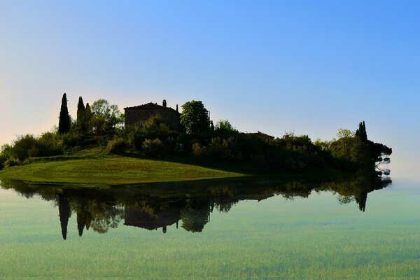 The house on the green island is reflected in the water