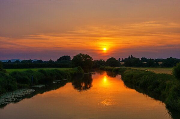 Il fiume scorre sotto il sole al tramonto