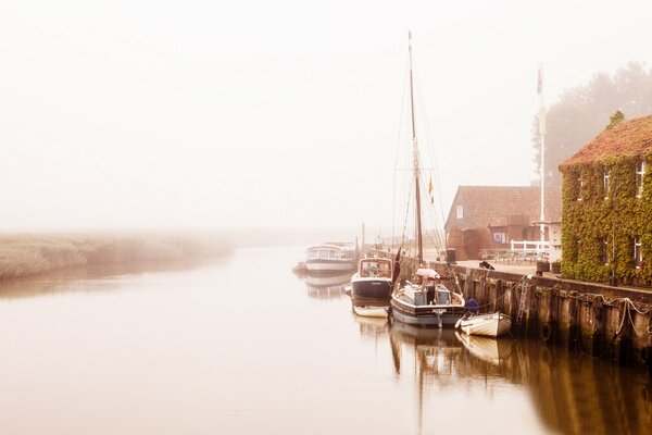 Quai avec des bateaux sur la rive de la rivière dans le brouillard