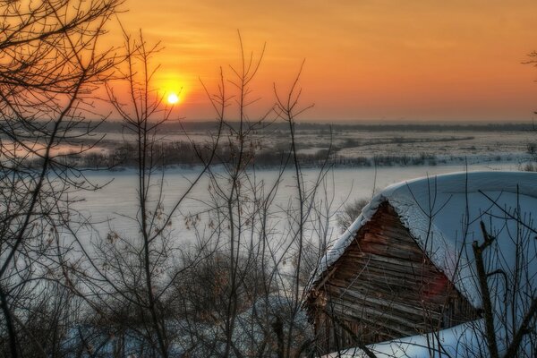 Sunset over winter forest and hut