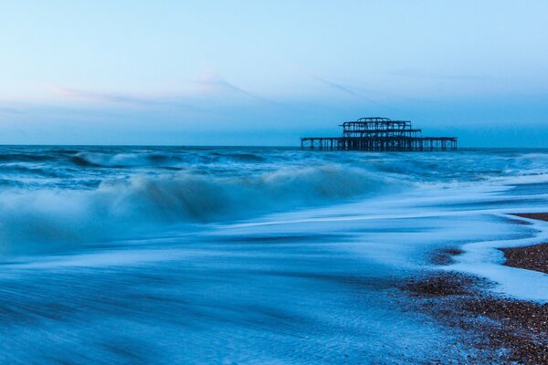 Stone beach, blue sky and raging waves