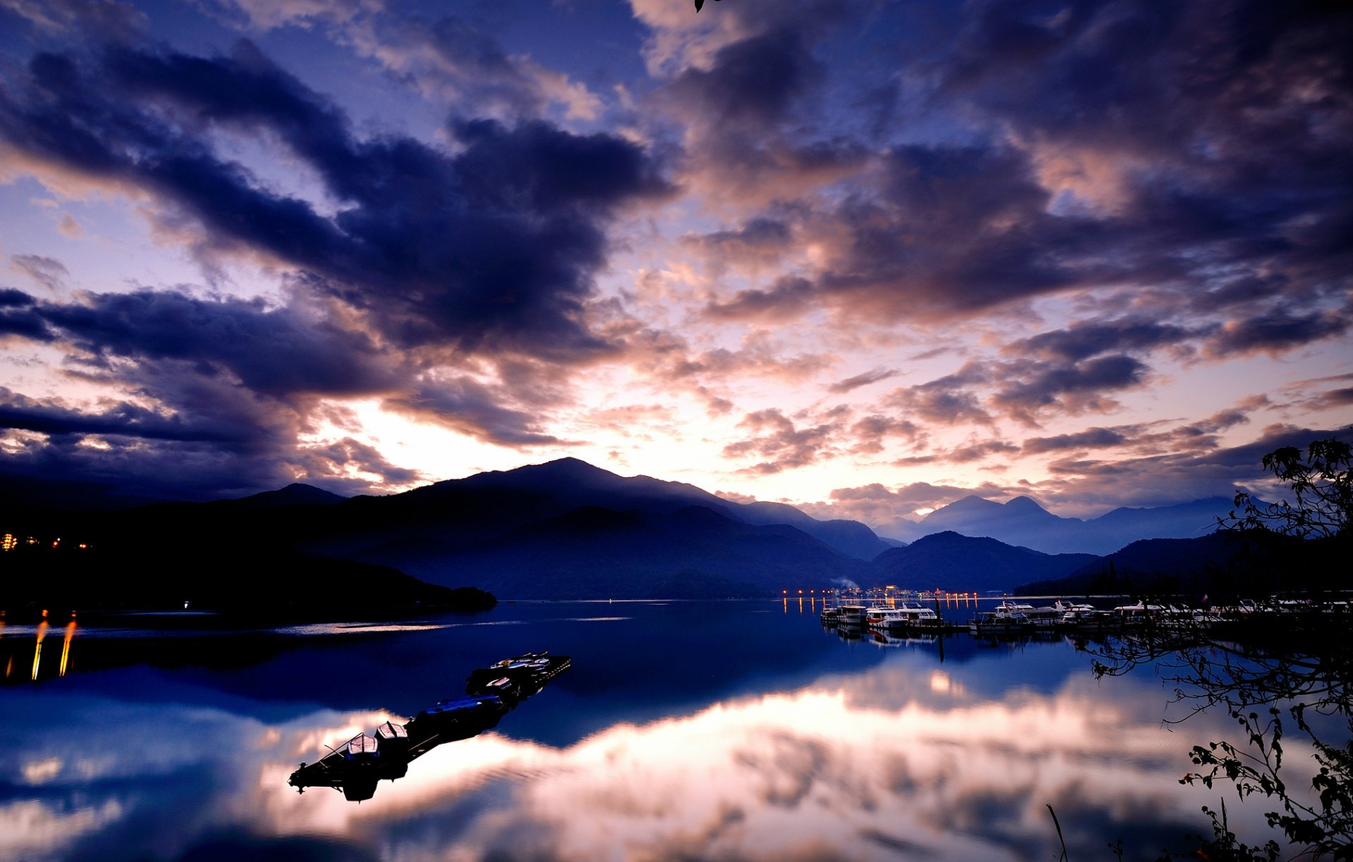 meer wasser oberfläche boote lichter berge hügel himmel blau wolken reflexion dämmerung