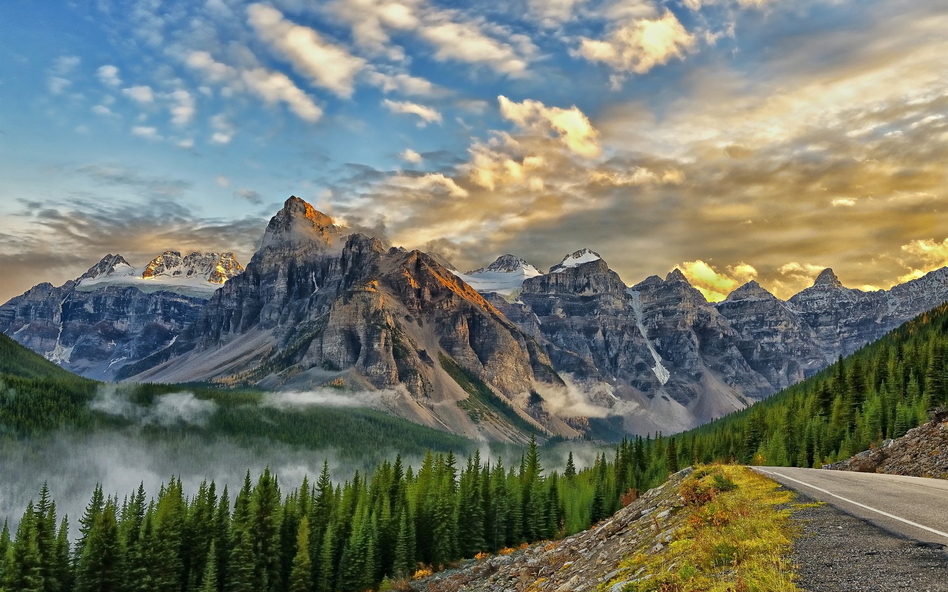 mountain road ridge snow fog clouds forest conifers tree