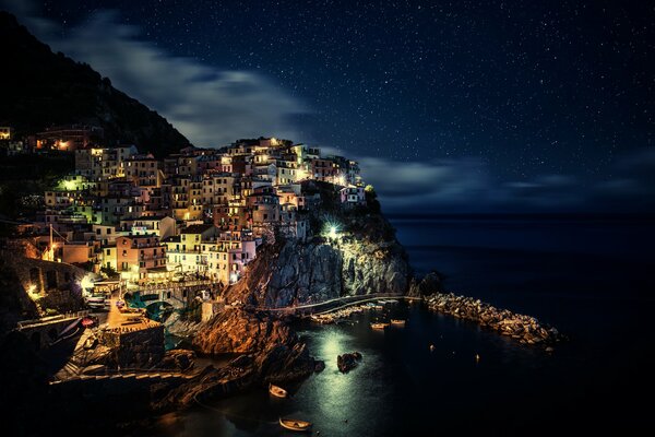 Blick auf das nächtliche Italien. Helle Lichter der Nachtstadt an der Küste