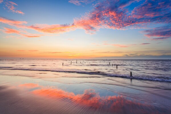 In der Bucht sind Stützen sichtbar und der Sonnenuntergang spiegelt sich im Wasser wider