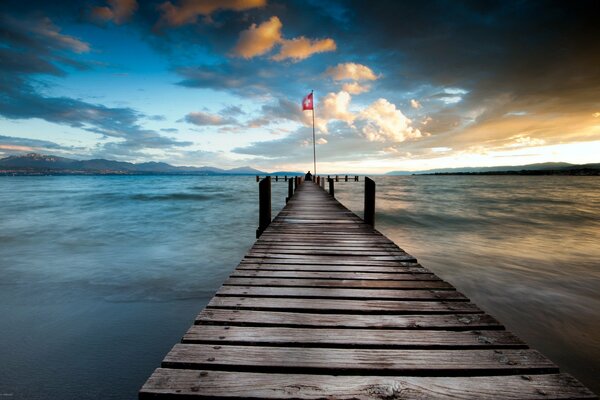 Un muelle que se adentra en el mar contra el cielo nublado de la tarde