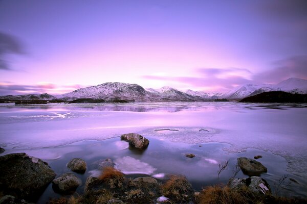 Montagne innevate e un lago ghiacciato al tramonto