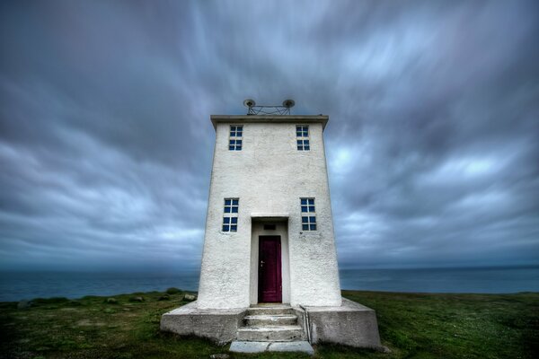 Faro in Islanda, su uno sfondo di cielo scuro con nuvole e paesaggio desertico