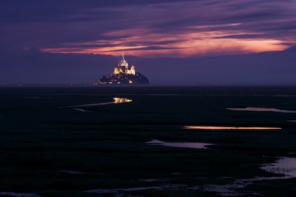 An illuminated fortress in the twilight of a purple sky