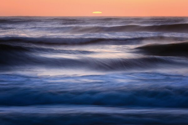 The sea surf and the sun setting over the horizon