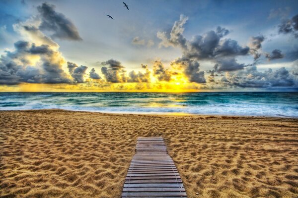 A sandy beach on the horizon a fire of the setting sun and leaden clouds