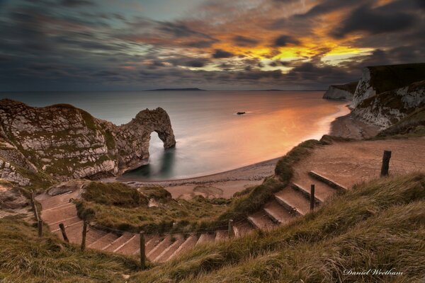 Treppe zum Meer und zum Bogen bei Sonnenuntergang