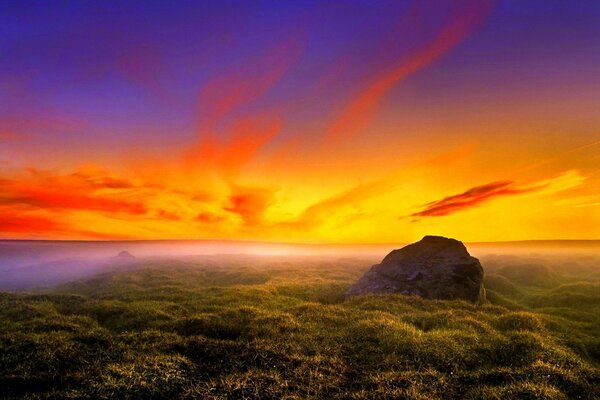 Llanura verde con piedra en el horizonte brillante amanecer