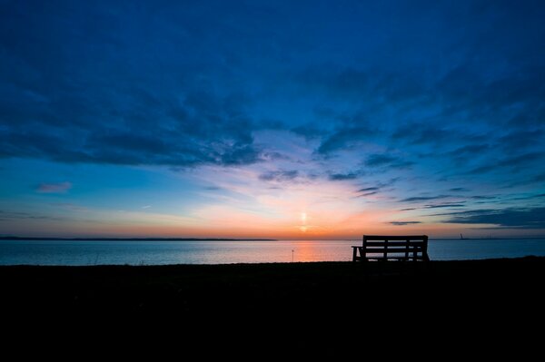 Landschaft mit einer Bank am Wasser bei Sonnenaufgang