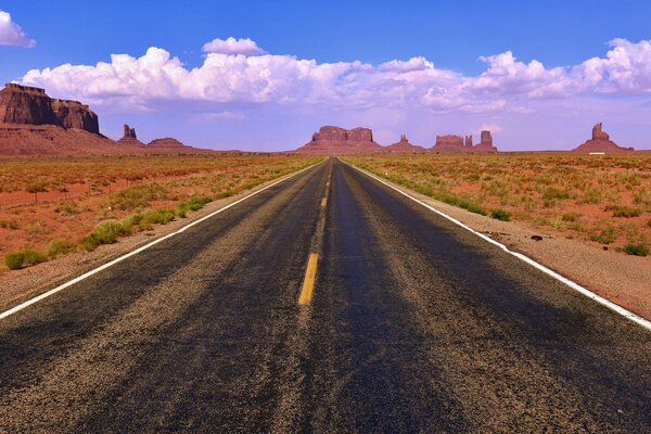 The road goes into the distance on the sides of landscapes of plains and rocks