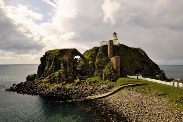 Phare sur la montagne sur fond de nuages blancs