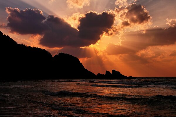 I raggi del sole si fanno strada attraverso le nuvole sul mare