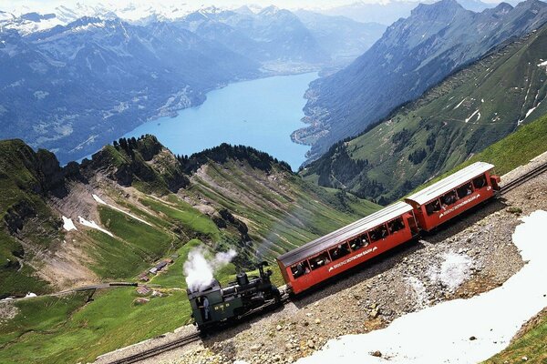 Abstieg der Dampflokomotive von den Bergen auf dem Hintergrund des Sees