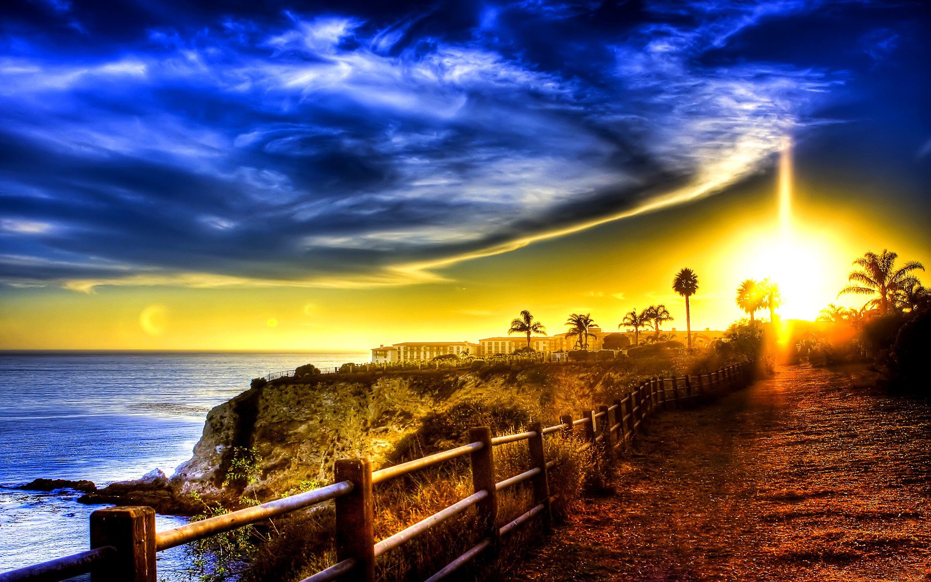 mar océano costa edificios carretera valla palmeras cielo nubes amanecer atardecer rayos luz