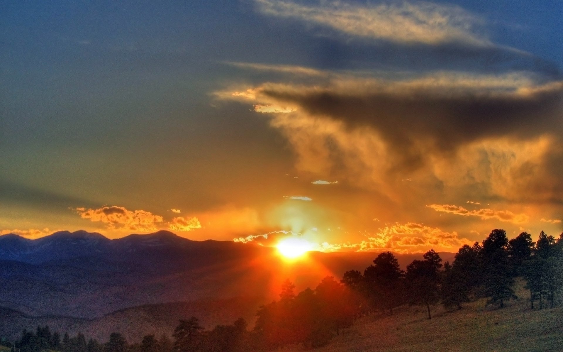 bosque árboles pendiente montañas colinas horizonte siluetas cielo nubes sol luz rayos puesta de sol nubes