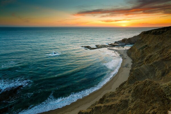 Waves beat against the shore in the sunset rays