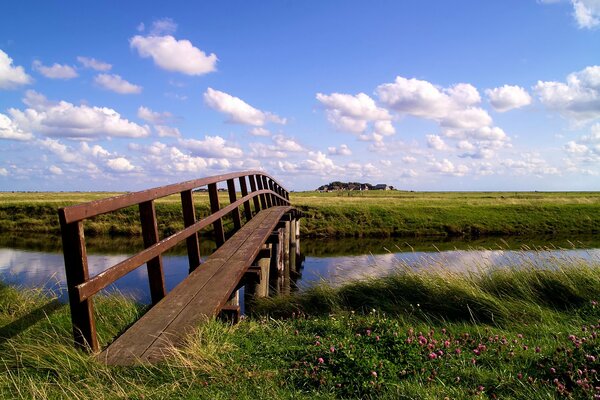 Un puente de madera sobre el río conecta dos campos