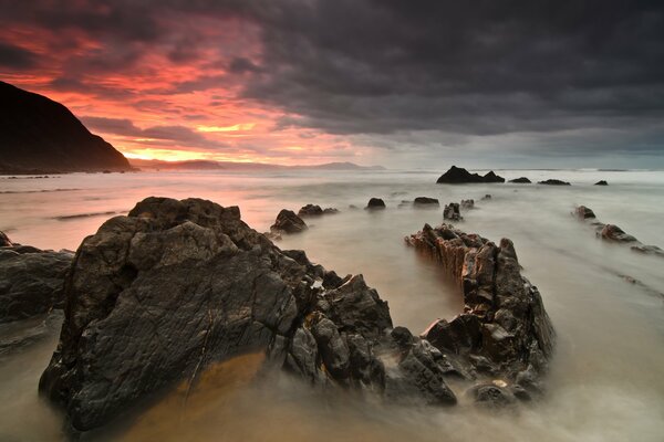 Red sunset over the sea with rocks