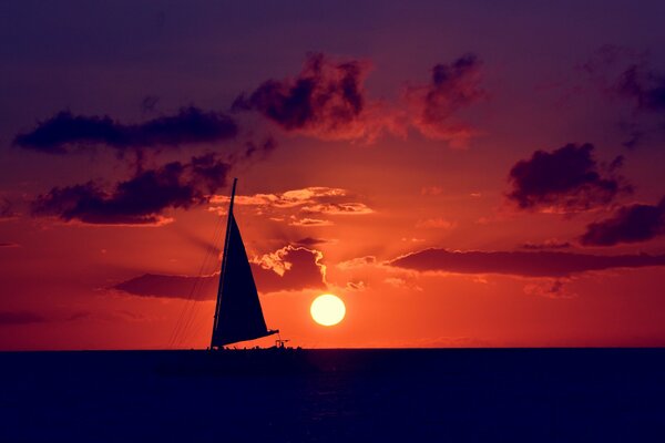 Sailboat in the sea on the background of sunset