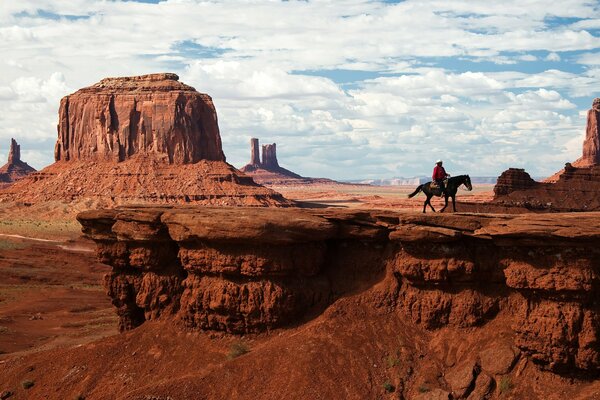 Kowboj jedzie na koniu w dolinie pomników