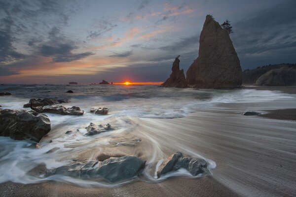Zachód słońca nad morzem morze obmywa kamienie