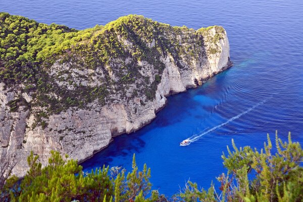 A boat floating on the sea along huge rocks