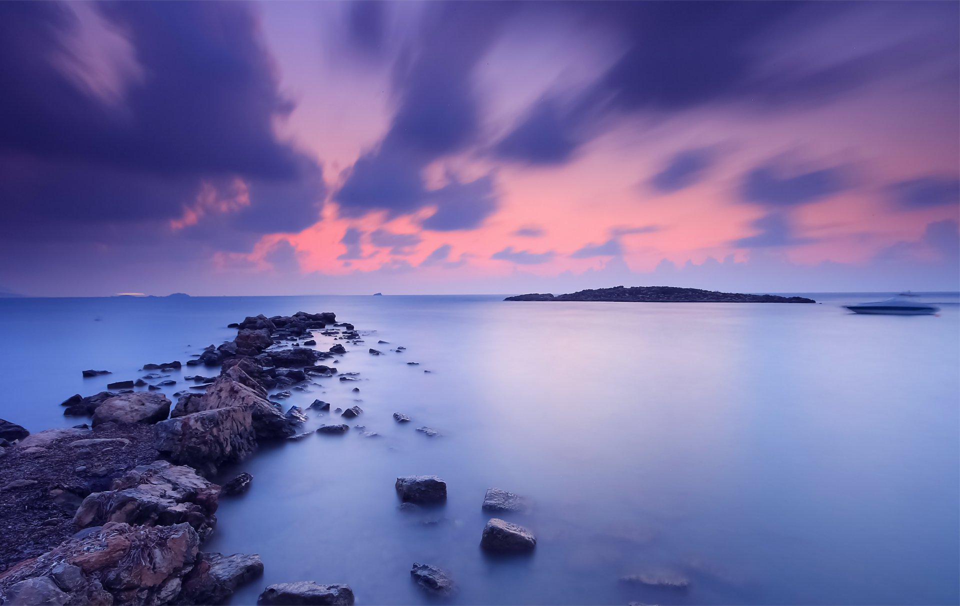 ea night orange sunset sky clouds beach stones water blue surface of calm boat away