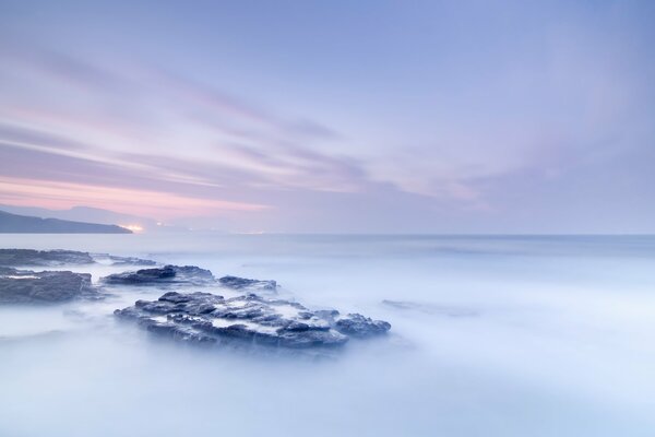 Misty dawn over rocks in the ocean