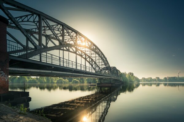 Ponte ad arco sul fiume fino all altra sponda dove splende il sole