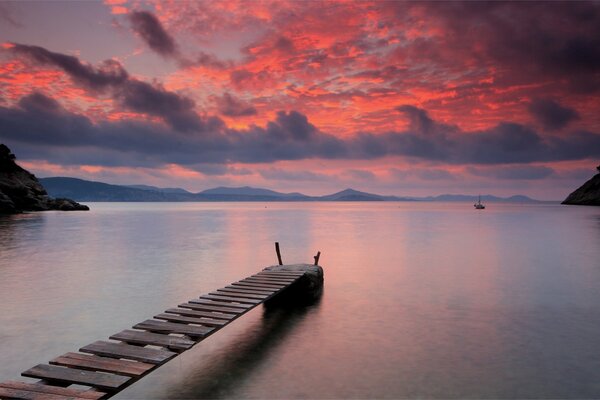 Pont en bois sur le lac. Coucher de soleil orange vif