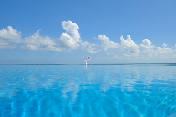 Blue transparent sea with a yogi reflecting white clouds