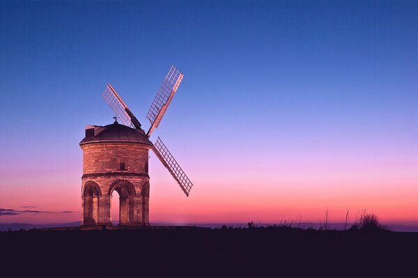 Pink sunset in the evening sky. Mill