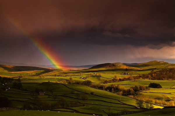 Arco iris en el cielo y colinas verdes