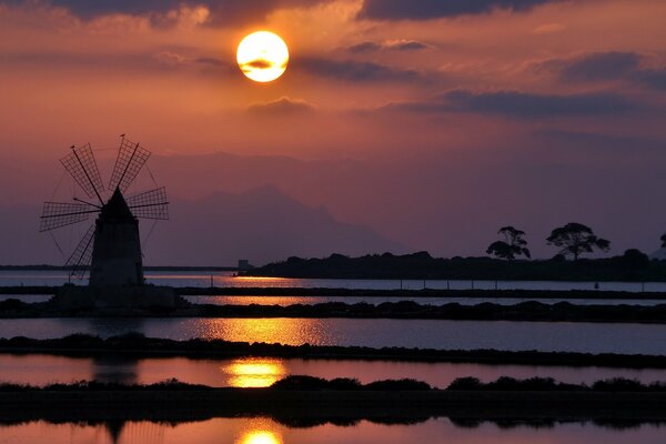 Reflexion der Mühle und der Sonne bei Sonnenuntergang