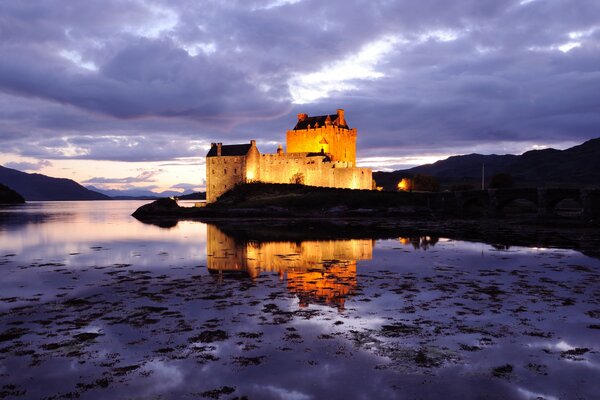 Illuminated castle in Scotland is reflected in the water