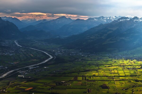 Valley of the mountains by the river at sunset