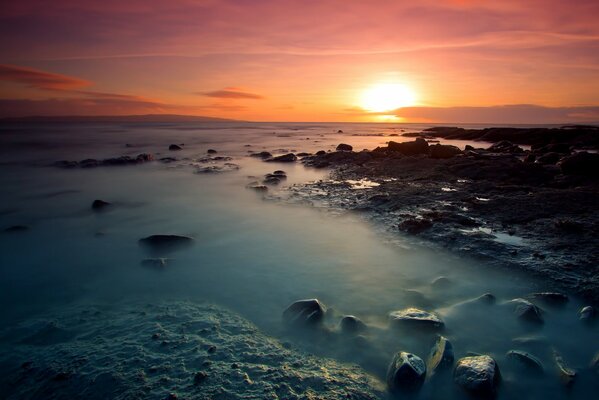 Jasny Zachód słońca na wybrzeżu ze skałami