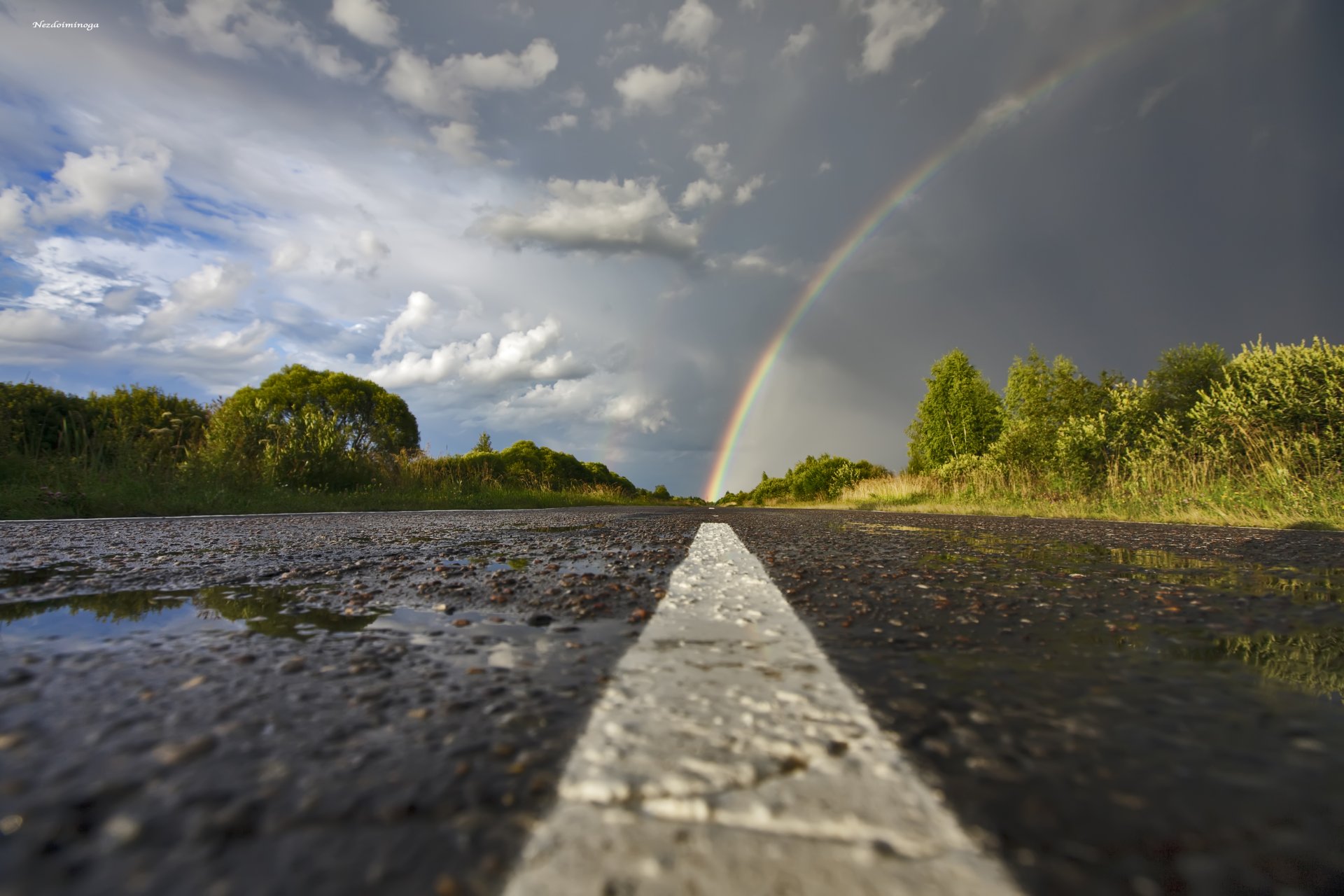 arco iris carretera asfalto charcos después de la lluvia cielo nubes árboles