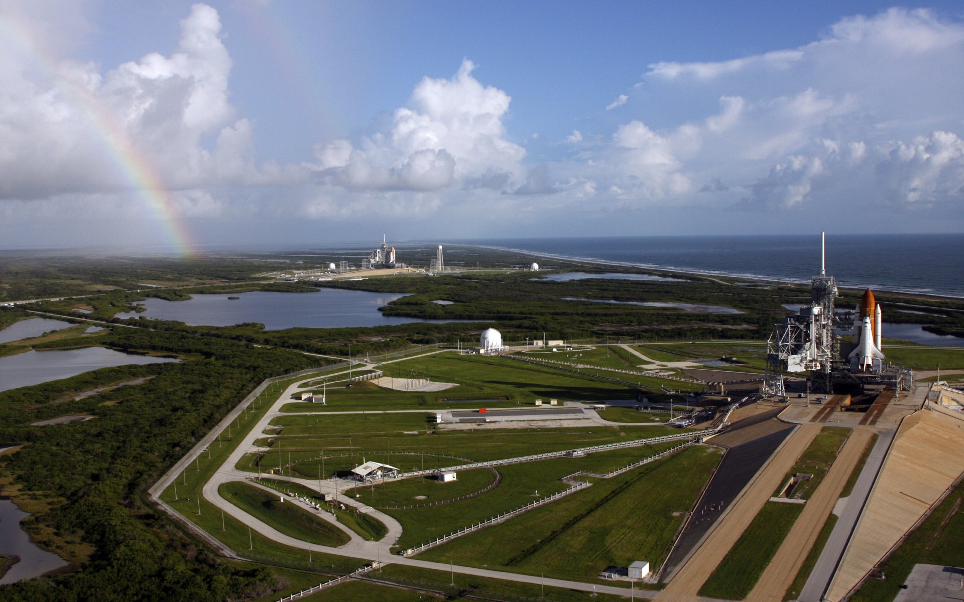 puerto espacial instalaciones transbordadores cohete vehículo de lanzamiento carreteras preparación costa arco iris horizonte cielo nubes