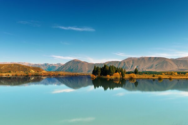 A blue lake, on the edges of which a rare forest grows. There are mountains in the distance