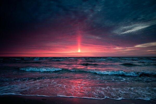 Roter Sonnenuntergang in den Meereswellen