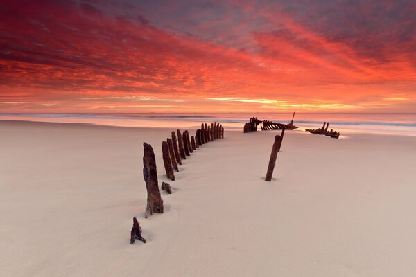 Meerstrand bei Sonnenuntergang mit Schiffsresten