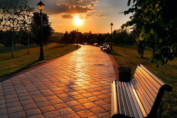 Park mit Bänken unter einem bewölkten Sonnenuntergang