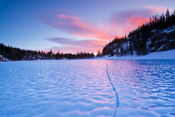 Fiume invernale con sponde boscose, alberi coperti di neve