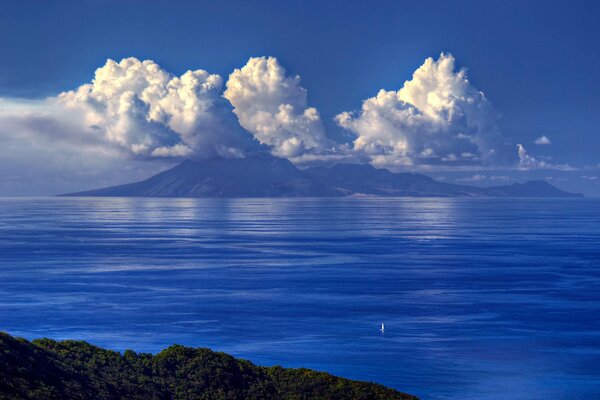 Voilier dans la mer sur fond de montagnes et de nuages